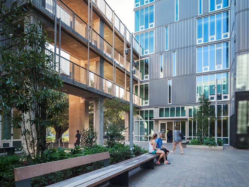 Contemporary courtyard with wooden and metal facade, green plantings, and concrete paving featuring seating areas by Adam Yarinsky.